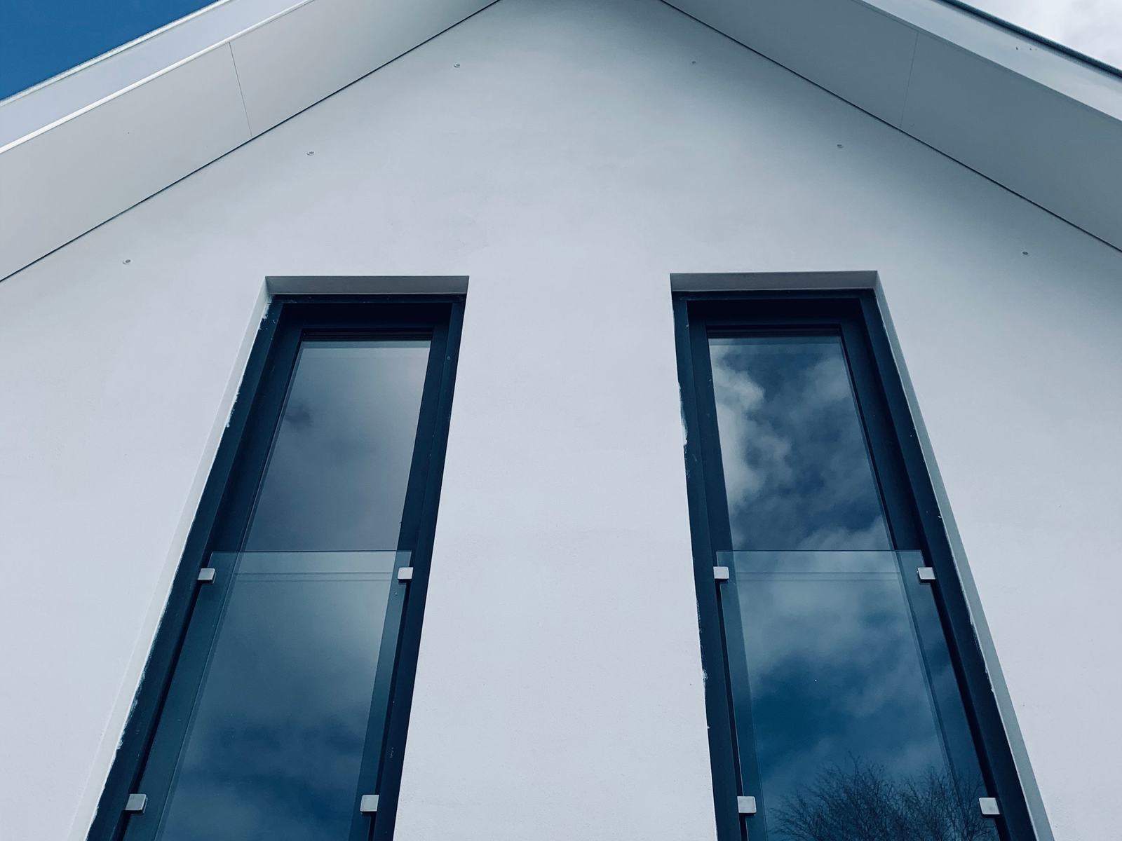 Fenêtres verticales à cadre foncé sur une façade blanche contemporaine