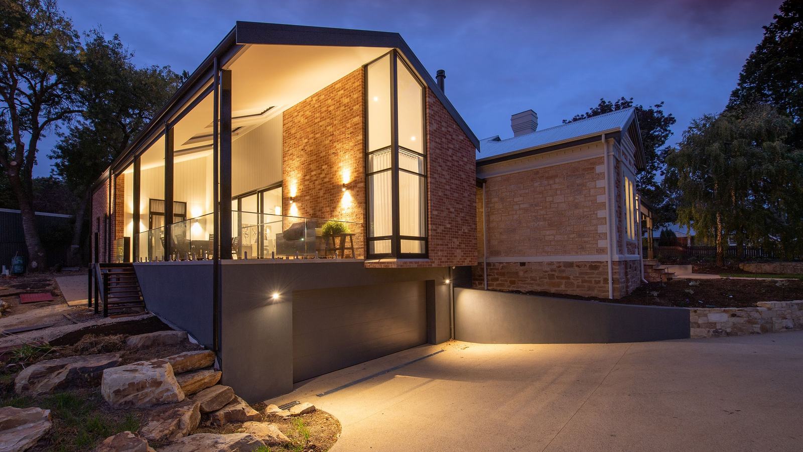 Maison contemporaine au crépuscule, larges fenêtres illuminées